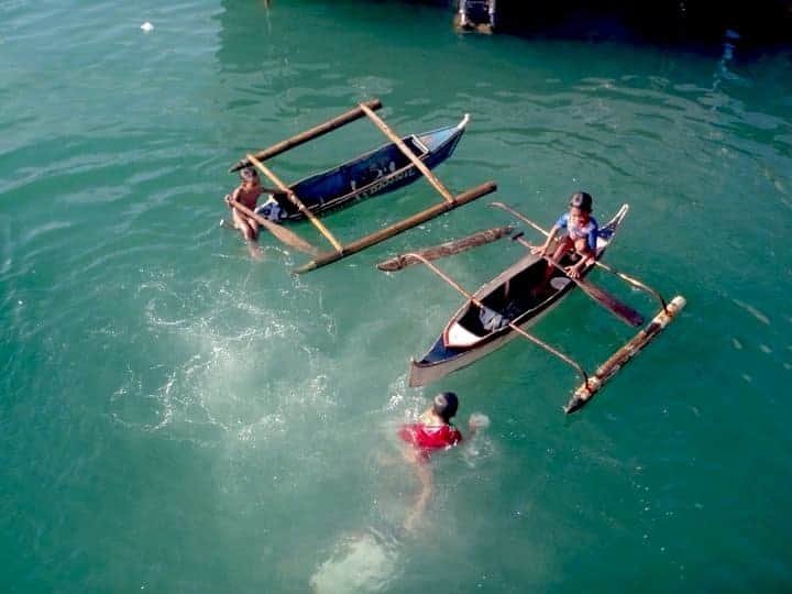 Poor children in wooden boats inside the sea