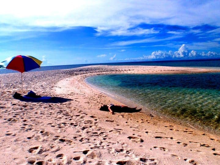 Laying on the beach with a colourful umbrella.