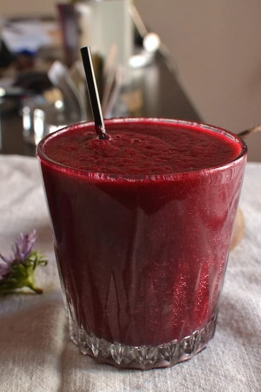 Beet smoothie in a glass with a black straw