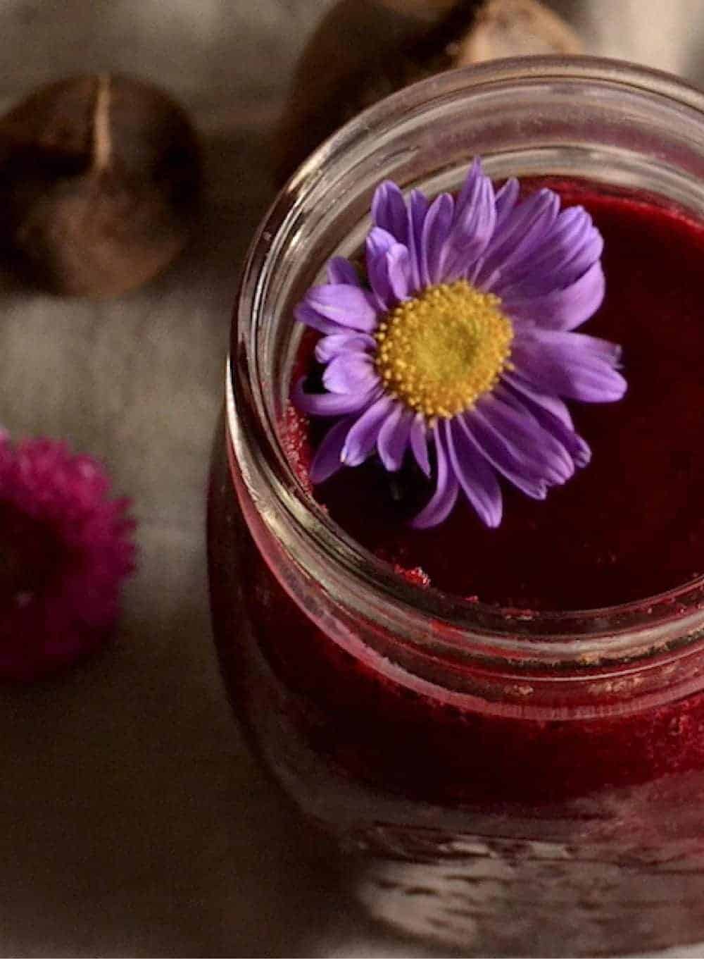 Beet smoothie in a jar with a purple flower