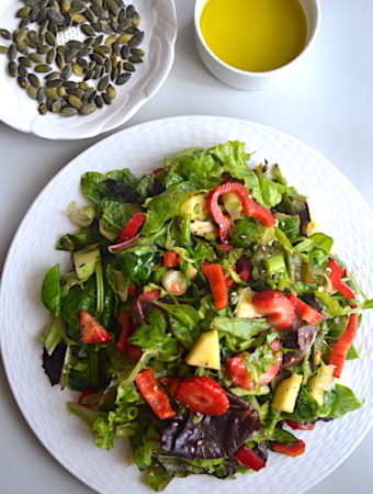 salad in white plate, sunfloer seeds and olive oil in white jar