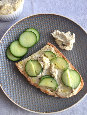 a slice of bread tossed with cocumbers and cheese cream in a grey plate.